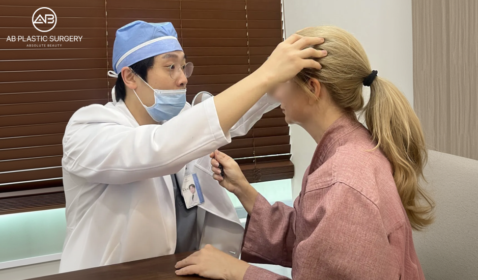 Plastic surgeon examining a patient’s forehead and facial proportions during a consultation for face liposuction and fat grafting planning