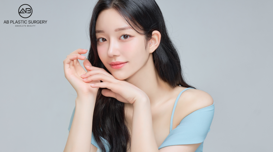 ผู้หญิงผิวใสหน้าหวาน สวมเสื้อสีฟ้า กำลังยิ้มอย่างมั่นใจ แสดงถึงผลลัพธ์การดึงหน้าแบบ SMAS ที่ช่วยยกกระชับผิวและกรอบหน้าให้ดูอ่อนเยาว์ เหมาะกับการรีวิวเทคนิค High SMAS และ Deep Plane Facelift